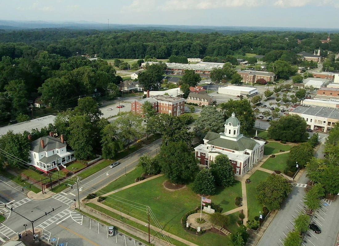 Contact - Aerial View of a Small Town in Downtown Georgia with Buildings Surrounded by Green Trees