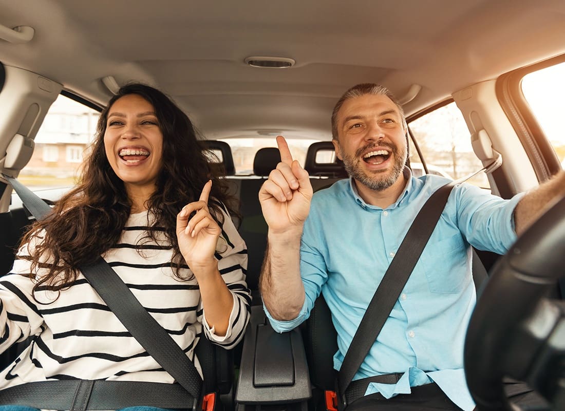 Insurance Solutions - Portrait of a Cheerful Middle Aged Man and Woman Having Fun Driving in a Car During a Road Trip